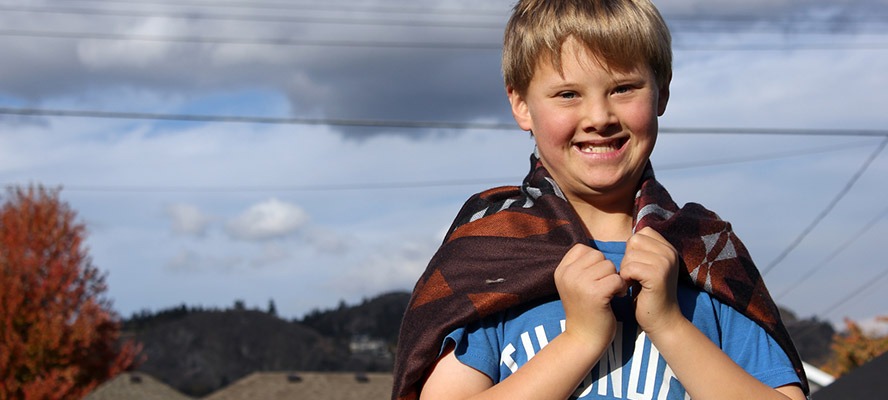 Photo of young boy using a blanket as a cape