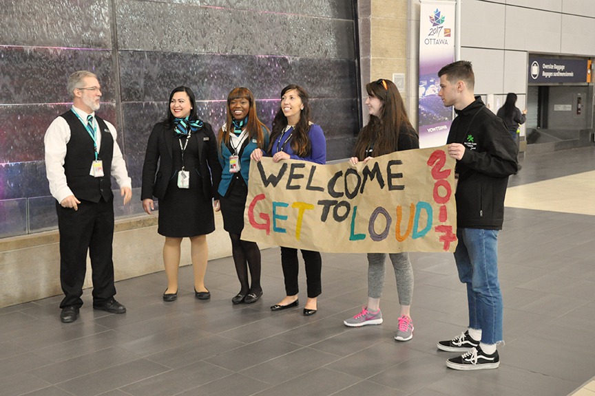 Youth holding a Welcome to Get Loud 2017 sign at the Ottawa airport